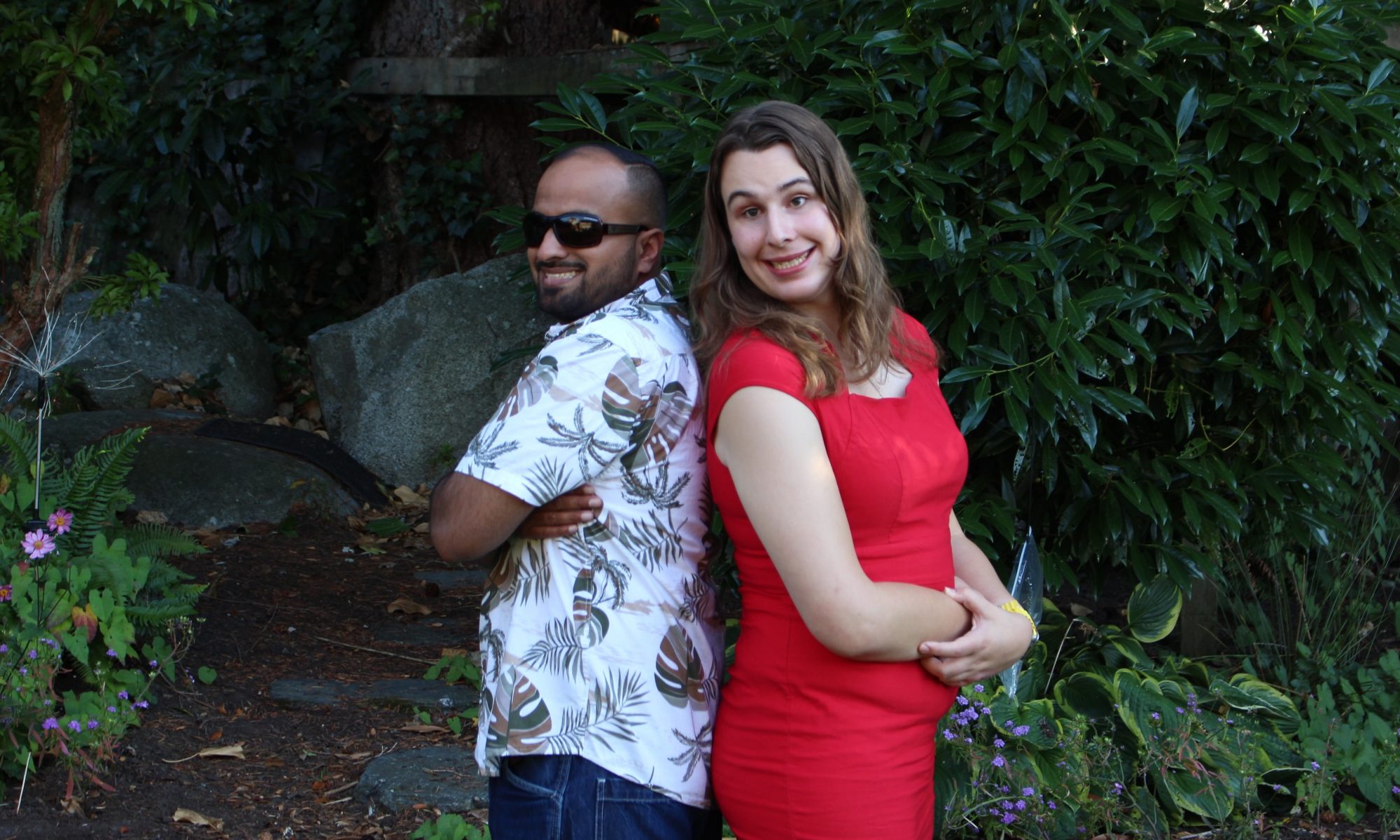 photo of Jugpreet Bajwa Sing, wearing a blue and white shirt and dark blue pants standing back to back with Justine Ongreen, waring a red