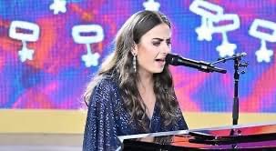 Lara pictured on the Carols By Candlelight stage last year on Christmas eve seated at a grand piano wearing a beautiful sparkly dark blue dress, singing and playing the piano.